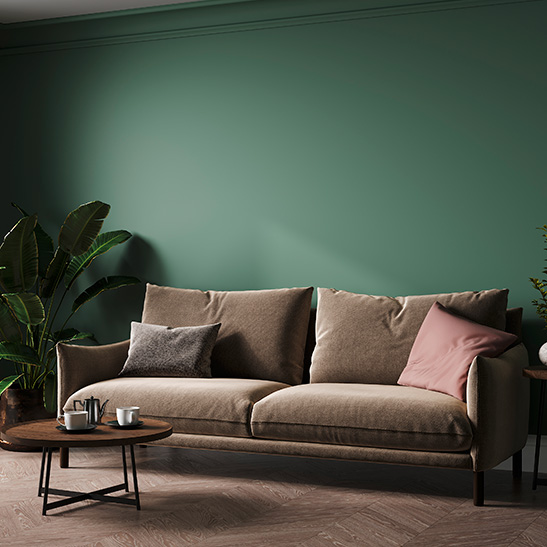 Grüne Wandgestaltung im Wohnzimmer mit einem braunen Sofa durch Malermeister